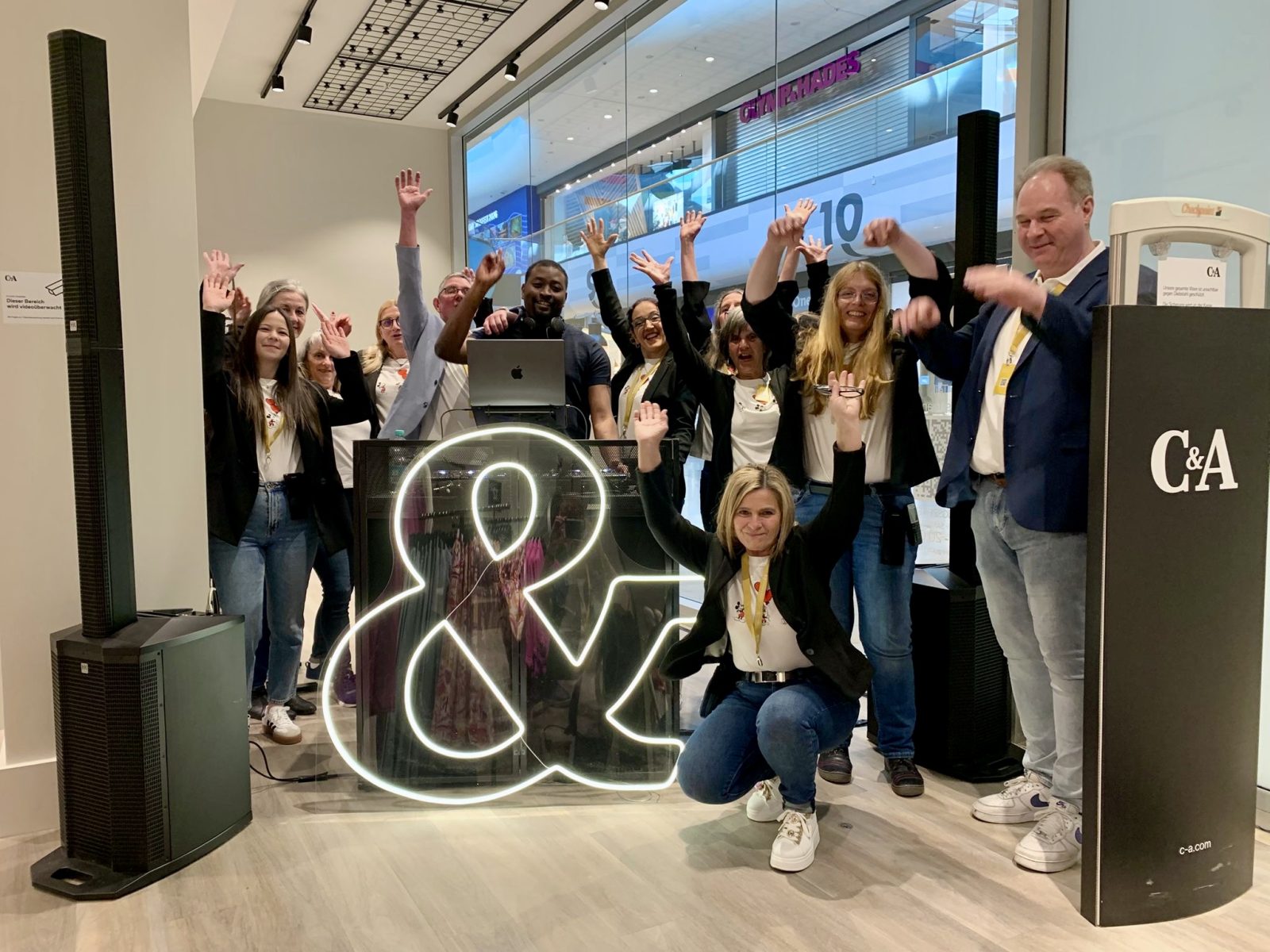 Team einer C&A Store-Eröffnung feiert vor dem DJ-Pult